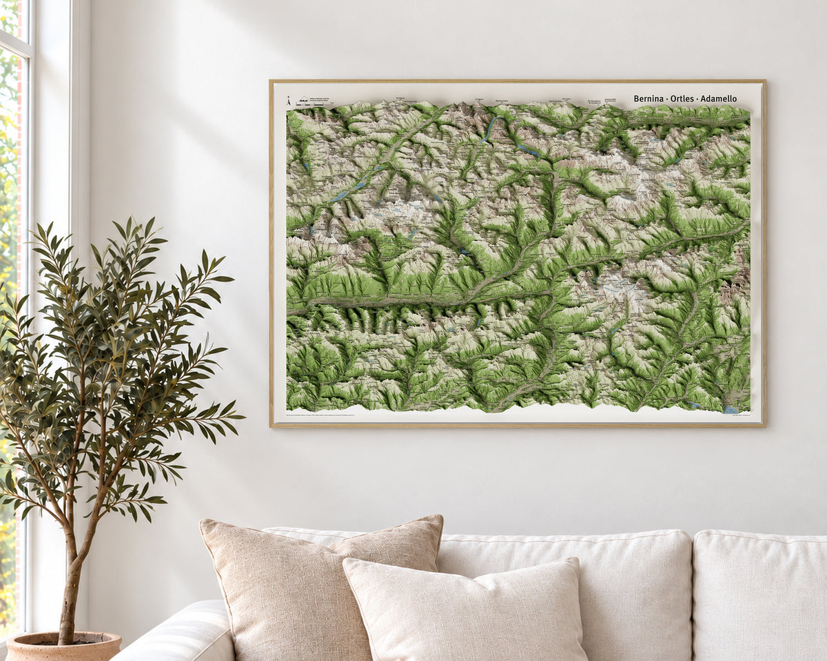 Mappa panoramica MountainCarto di Bernina, Ortles e Adamello, incorniciata sopra un divano chiaro · Framed MountainCarto panoramic map of Bernina, Ortles and Adamello above a light-coloured sofa